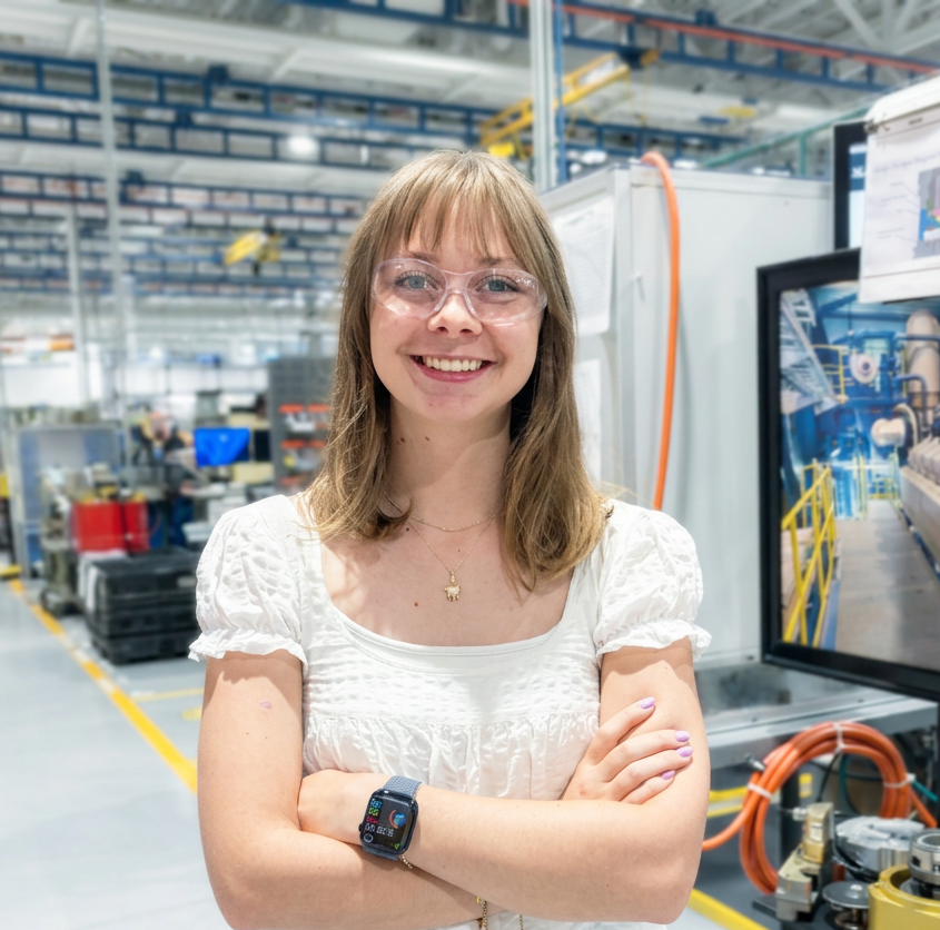 Young woman with folded arms standing on manufacturing floor