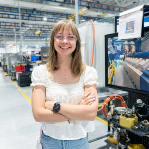 Young woman posing on manufacturing floor in front of her engineering project