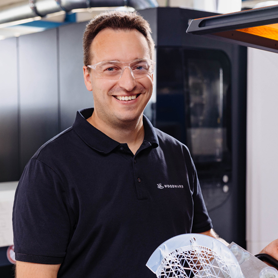 Woodward Member Man wearing safety goggles working on manufacturing floor